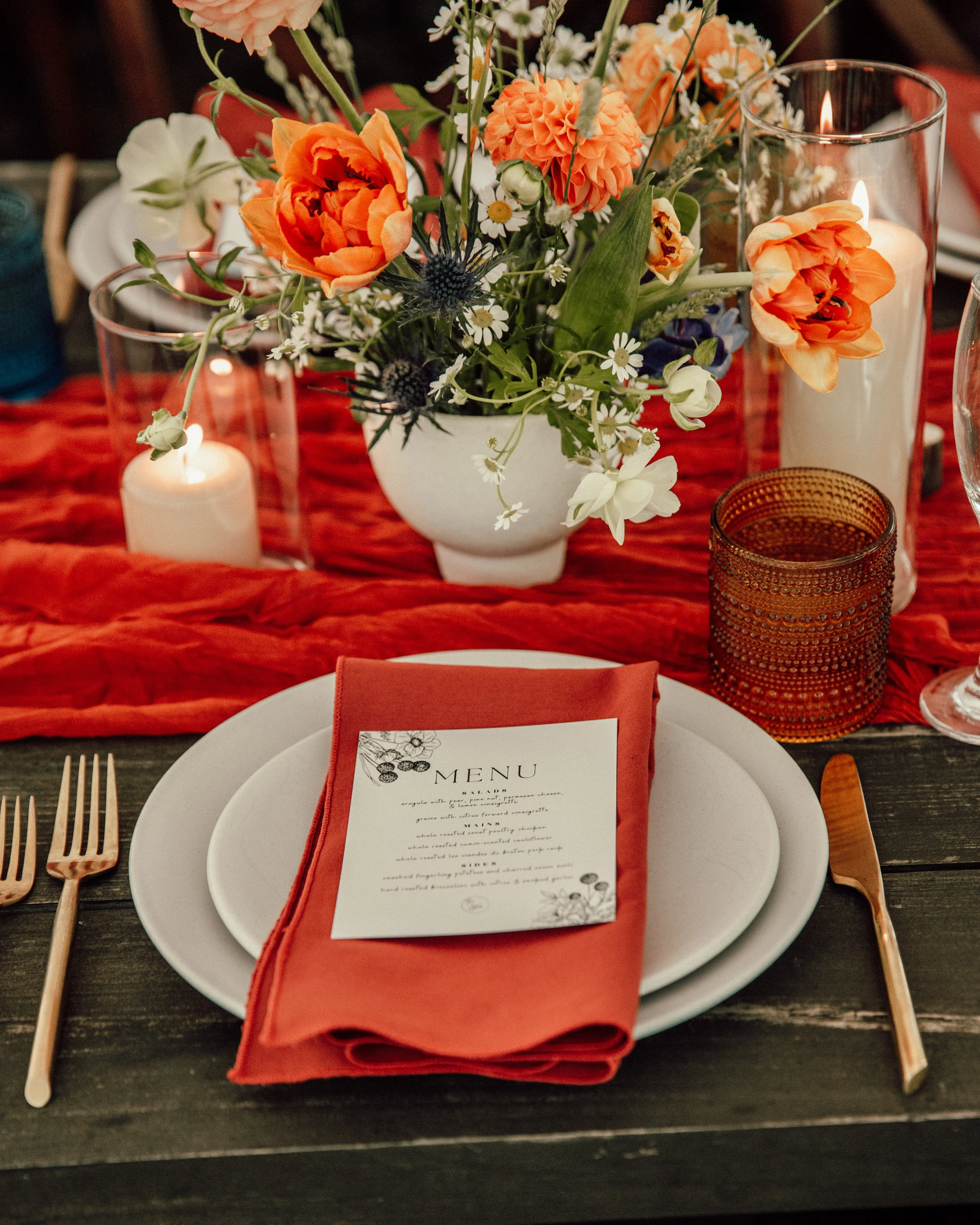 Place setting with menu card and an orange dahlia and ranunculus centerpiece at Glen Falls House