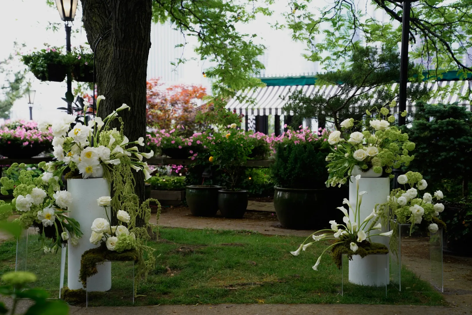Ceremony aisle at River Cafe flanked by matching white pedestal floral arrangements under the trees