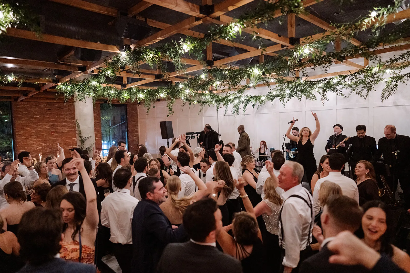 Guests dancing under the string-lit greenery canopy as the band performs
