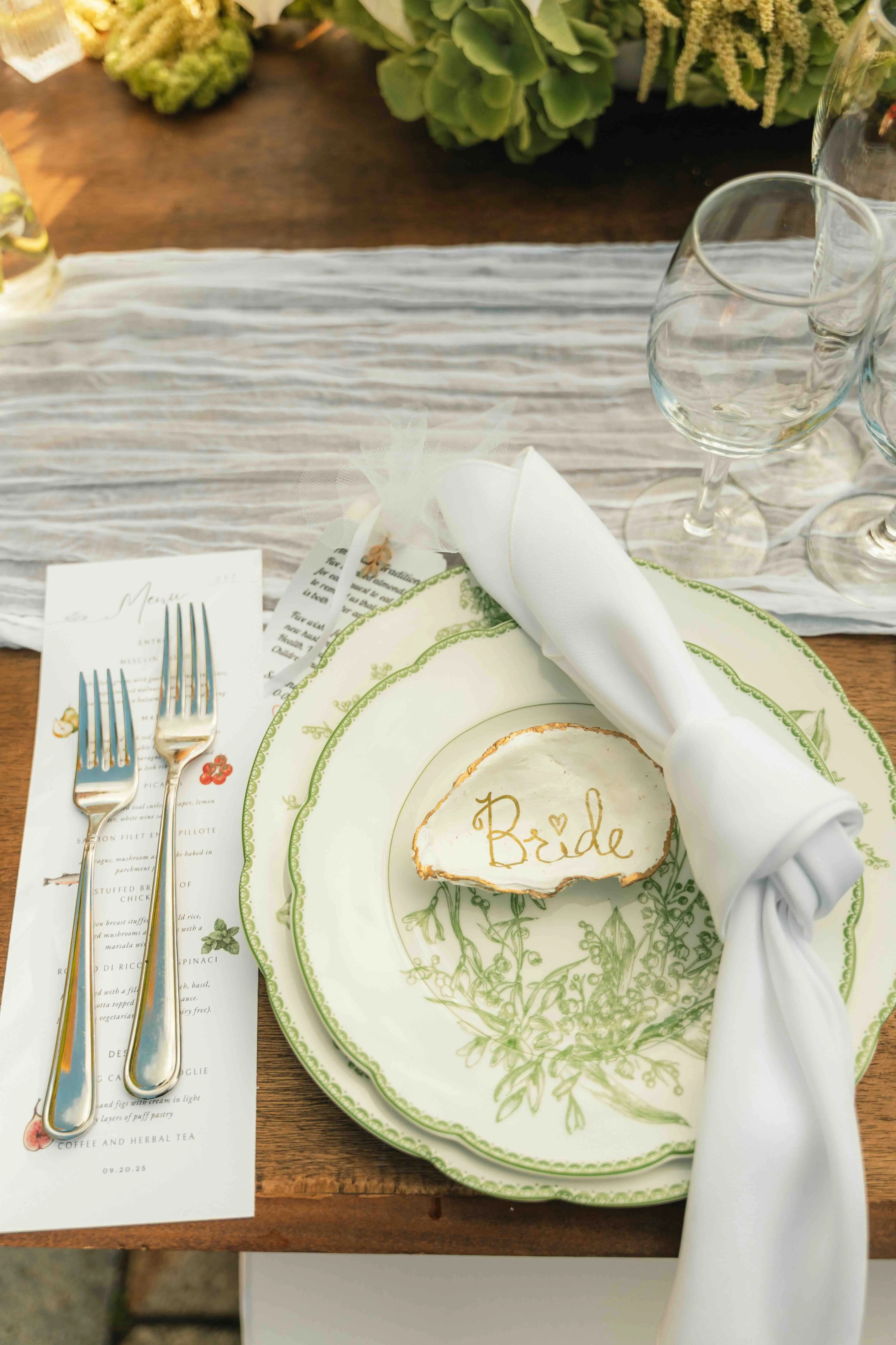 Bride's place setting with a gold-lettered agate place card and green floral-patterned china