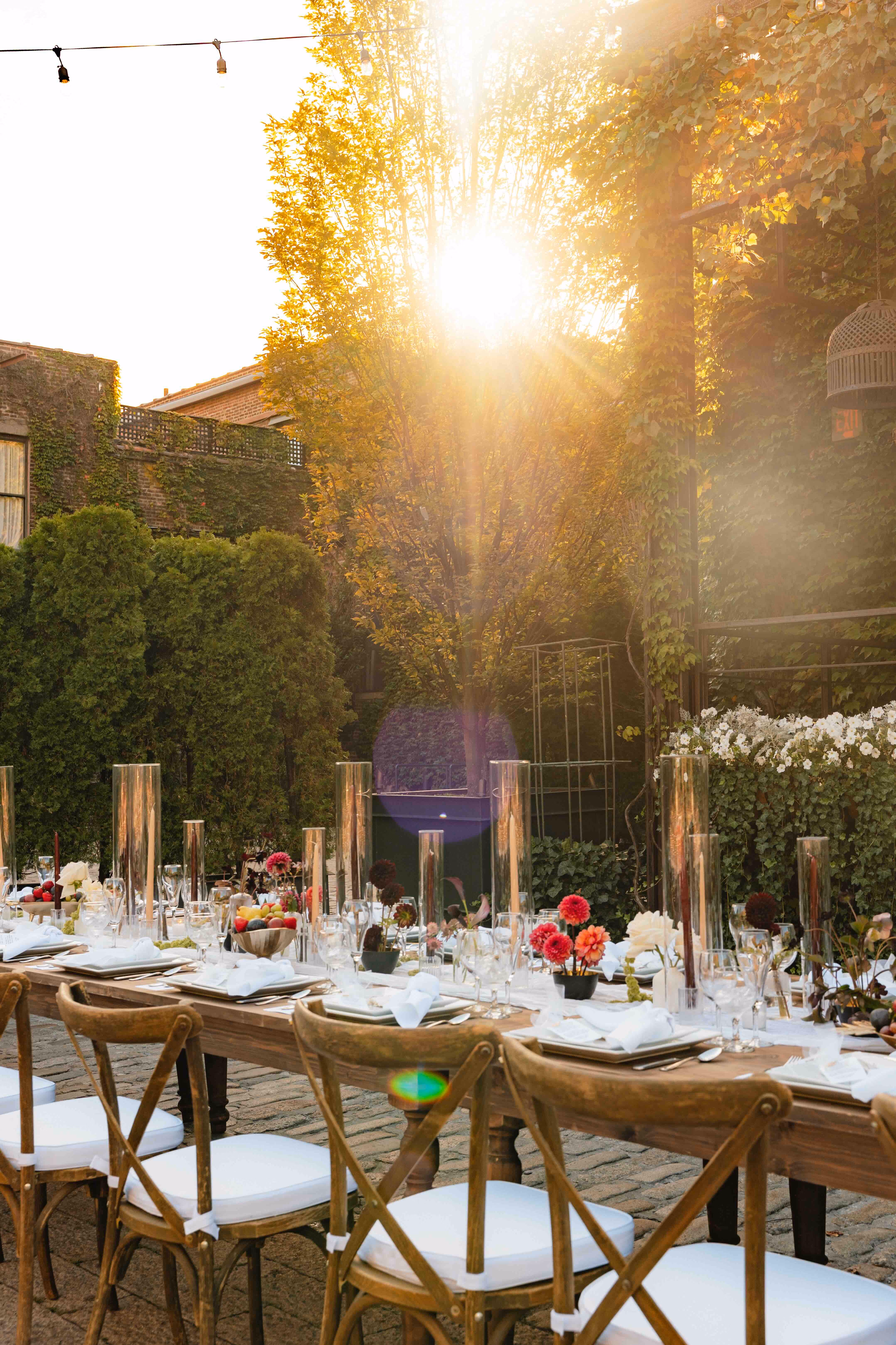 Golden hour view of the outdoor reception table set beneath string lights and trees
