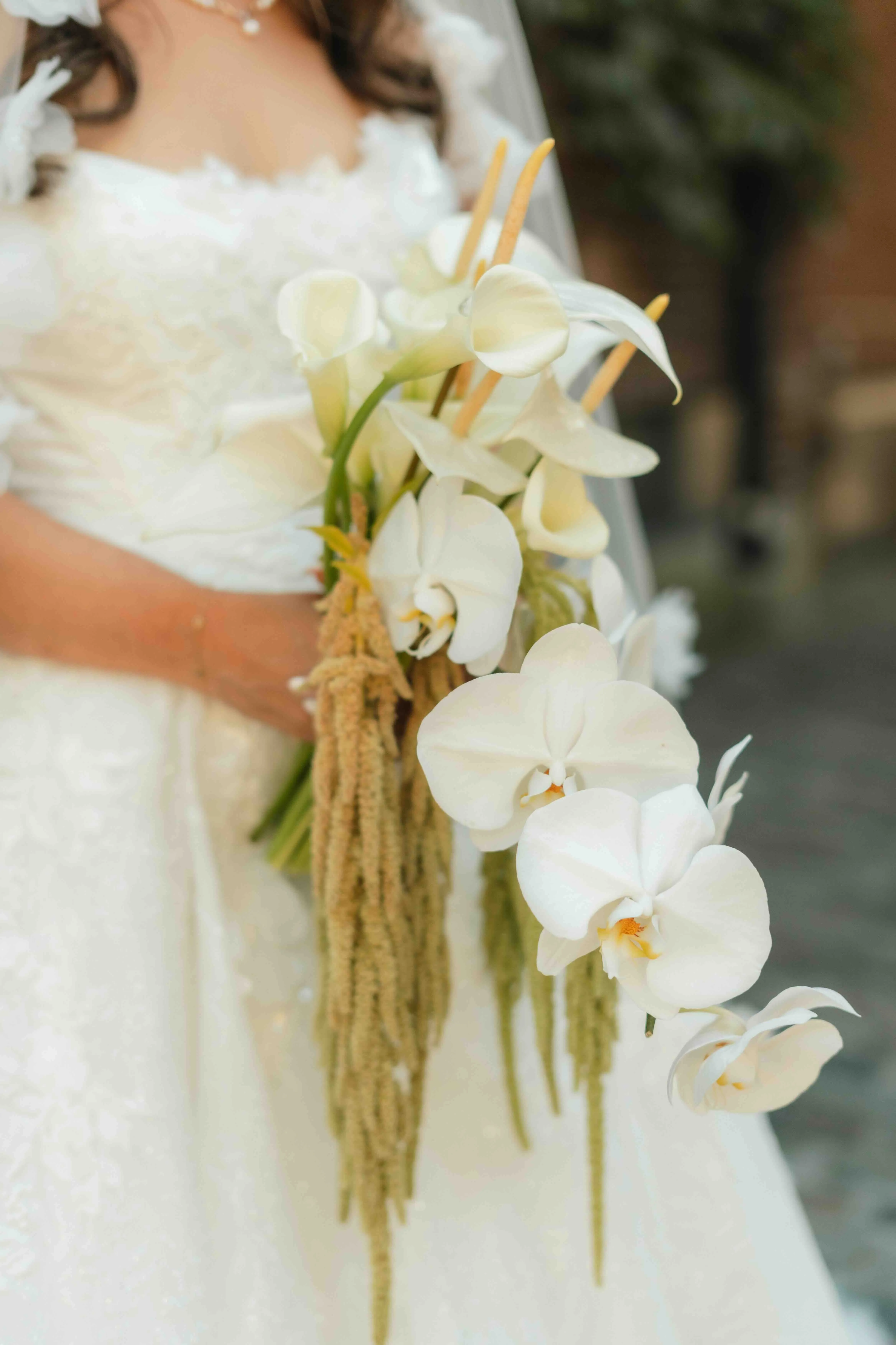 Cascading bridal bouquet of white orchids, calla lilies, and trailing amaranthus