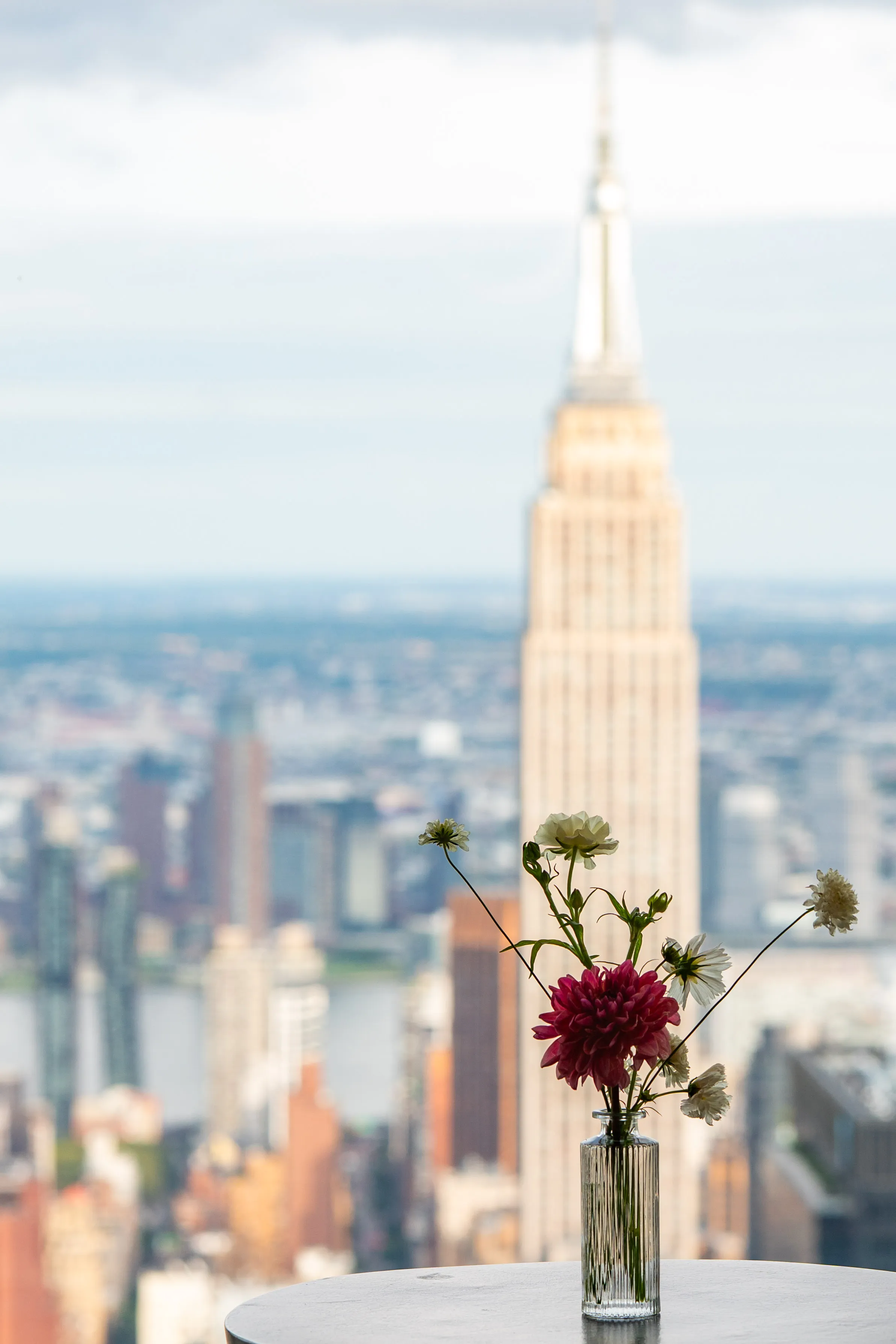 Small dahlia and wildflower arrangement in a glass vase overlooking the Empire State Building