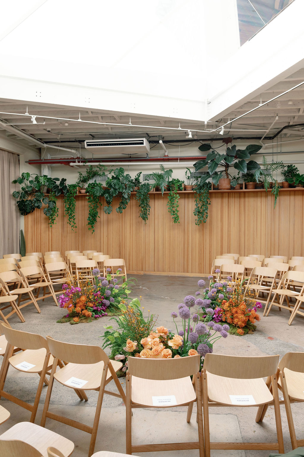 Ceremony space arranged in a circle with orange and purple floral clusters on the floor beneath a skylight