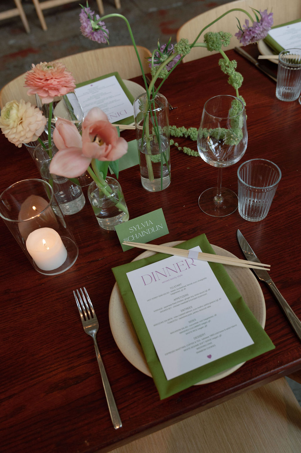 Place setting with dinner menu, name card, and bud vases of pink dahlias and tulips