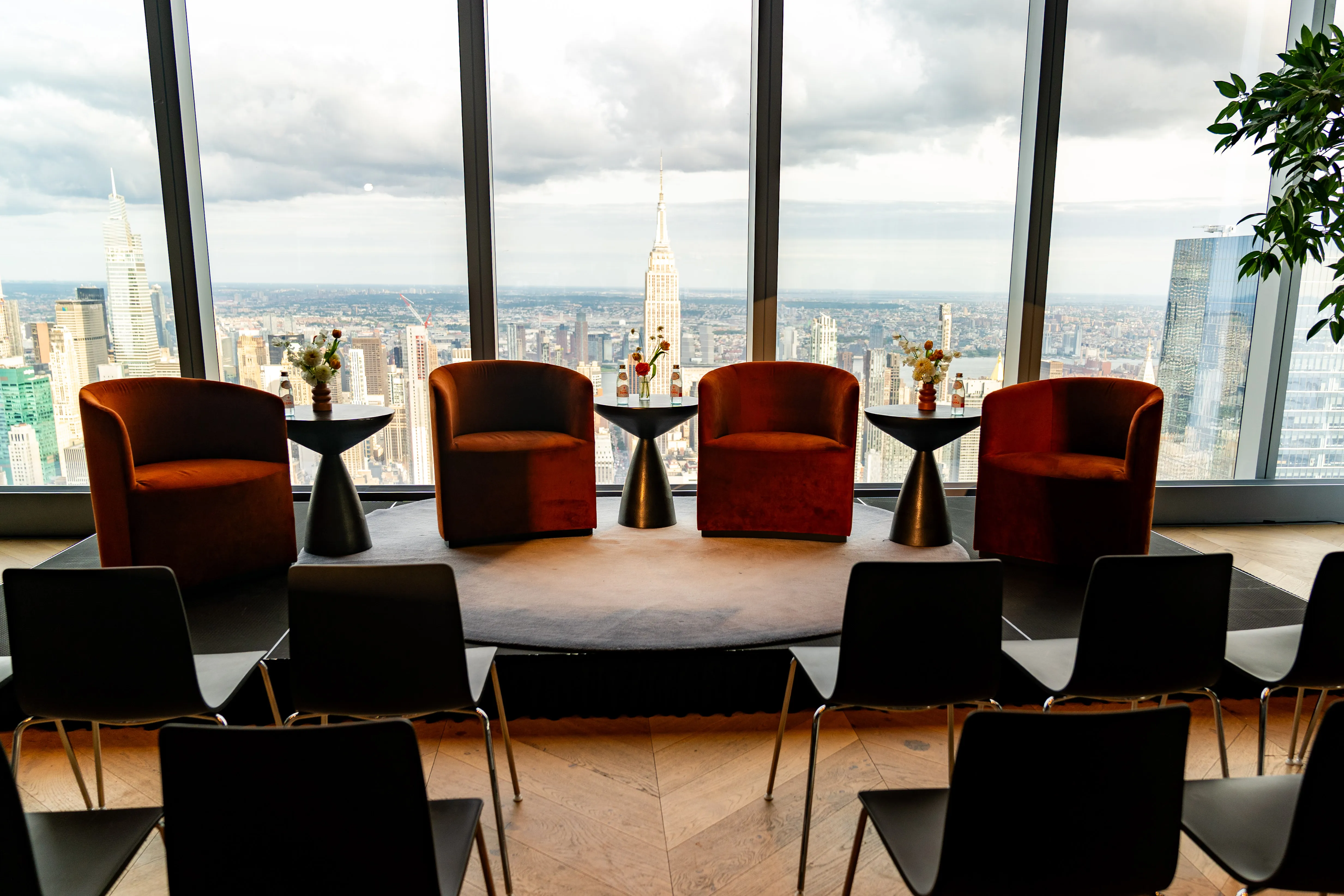 Velvet lounge chairs arranged for a rooftop corporate event with an Empire State Building skyline view