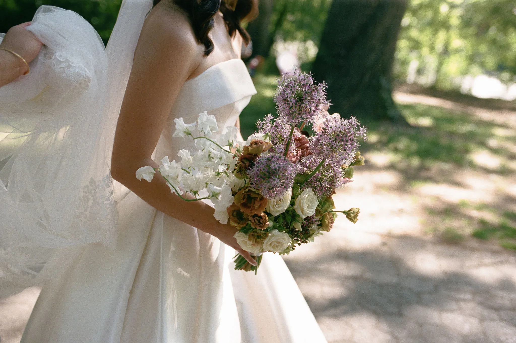 Floral ceremony arch with allium, garden roses, and greenery framing the lake, with white chairs set for guests.