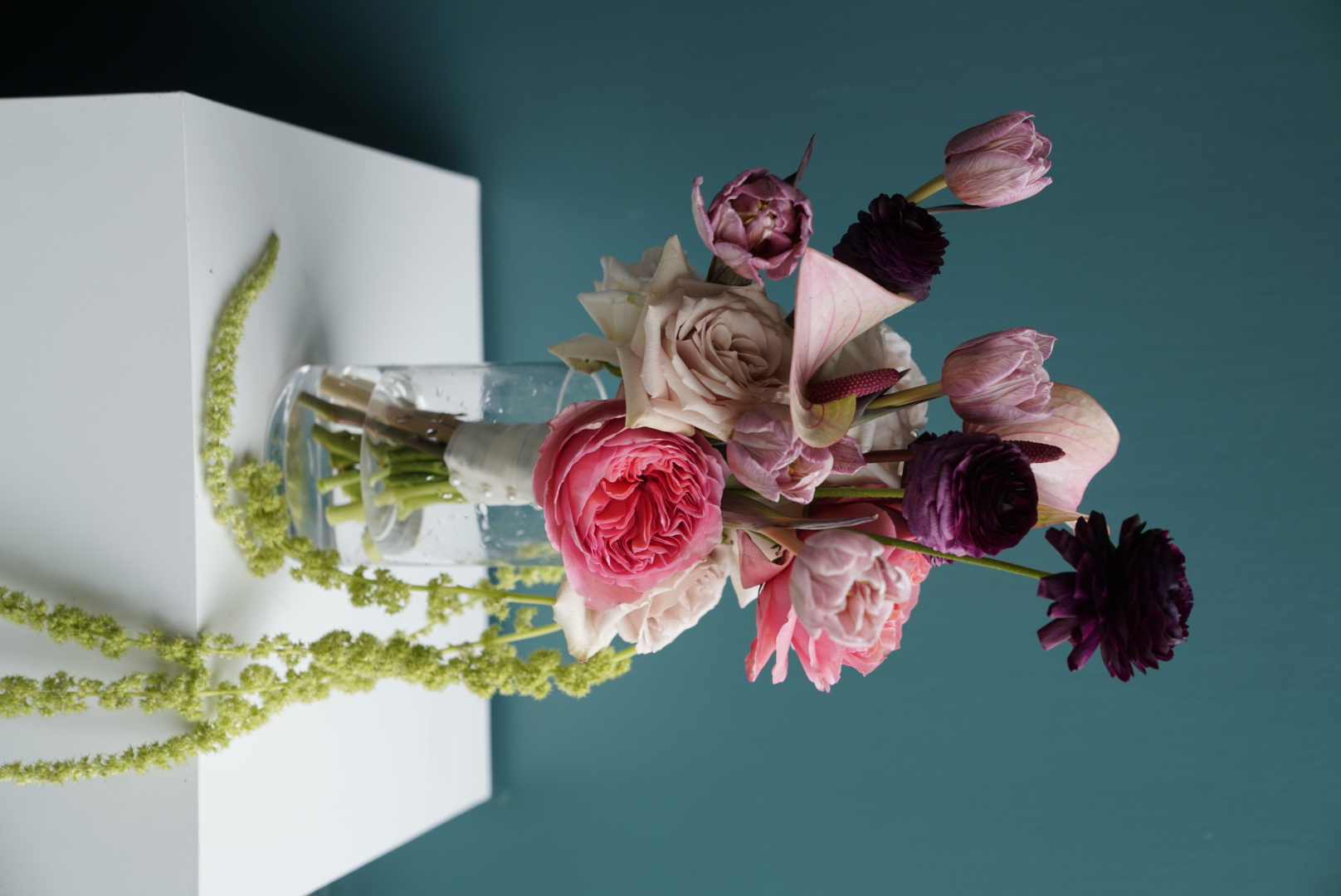 Pink and burgundy roses with tulips and trailing amaranthus in a glass vase