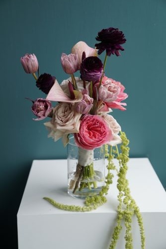 Pink and burgundy roses with tulips and trailing amaranthus in a glass vase