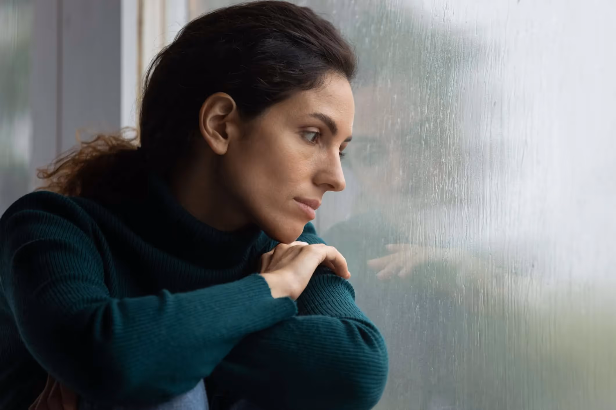 A woman survivor looks out the window somberly. 