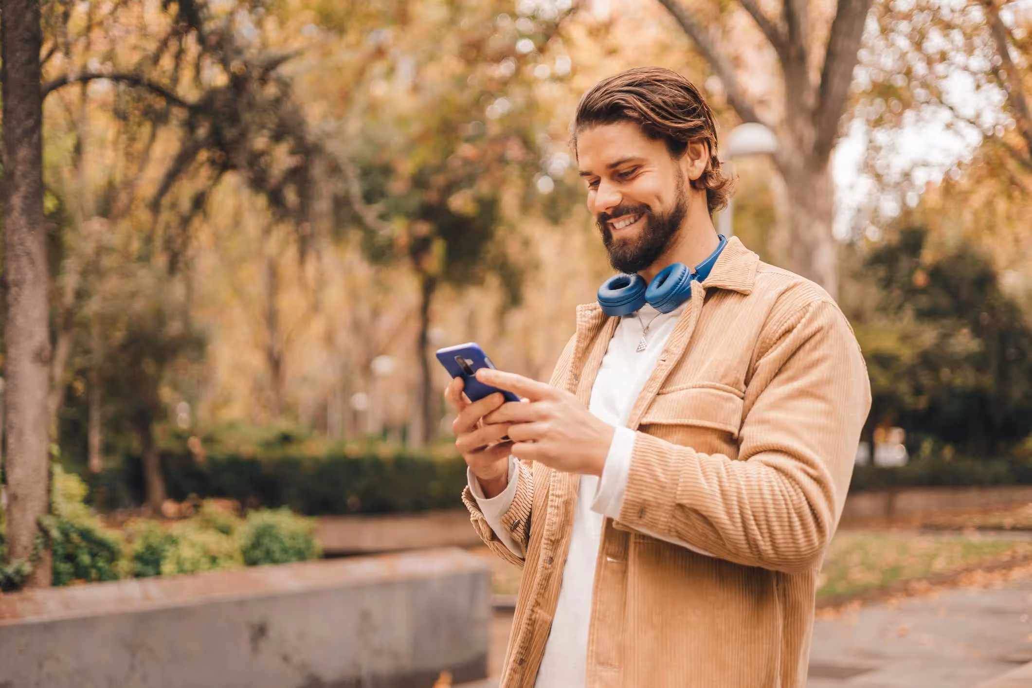 Caucasian man walking through a park learning how to prevent phones exploding while charging.