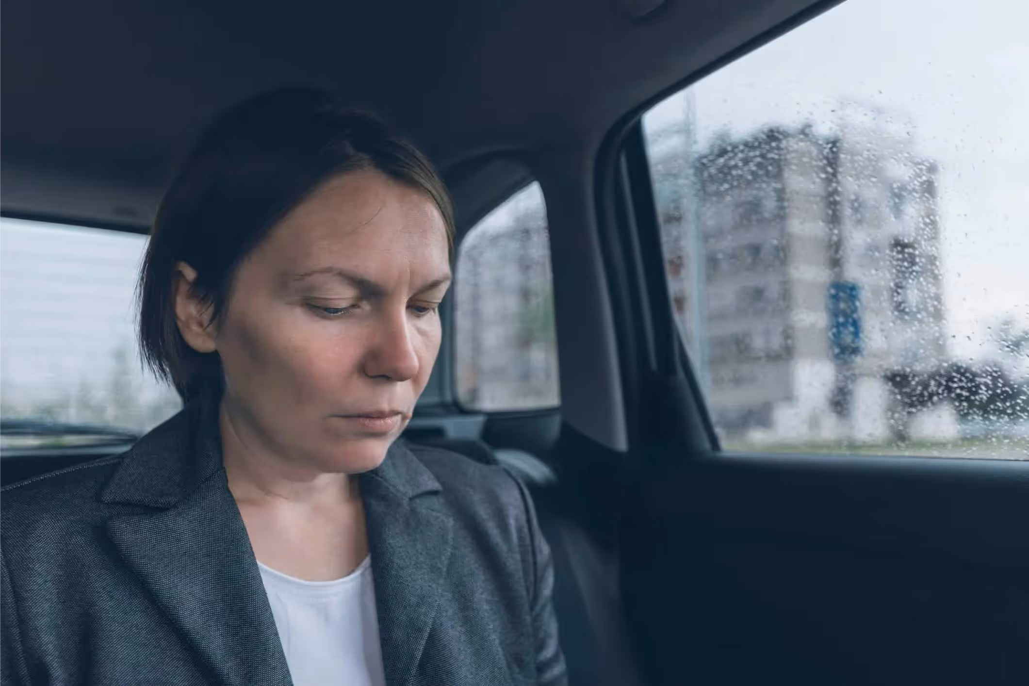 Woman sitting in the back seat of a car at night, representing cases handled by rideshare sexual assault lawyers.