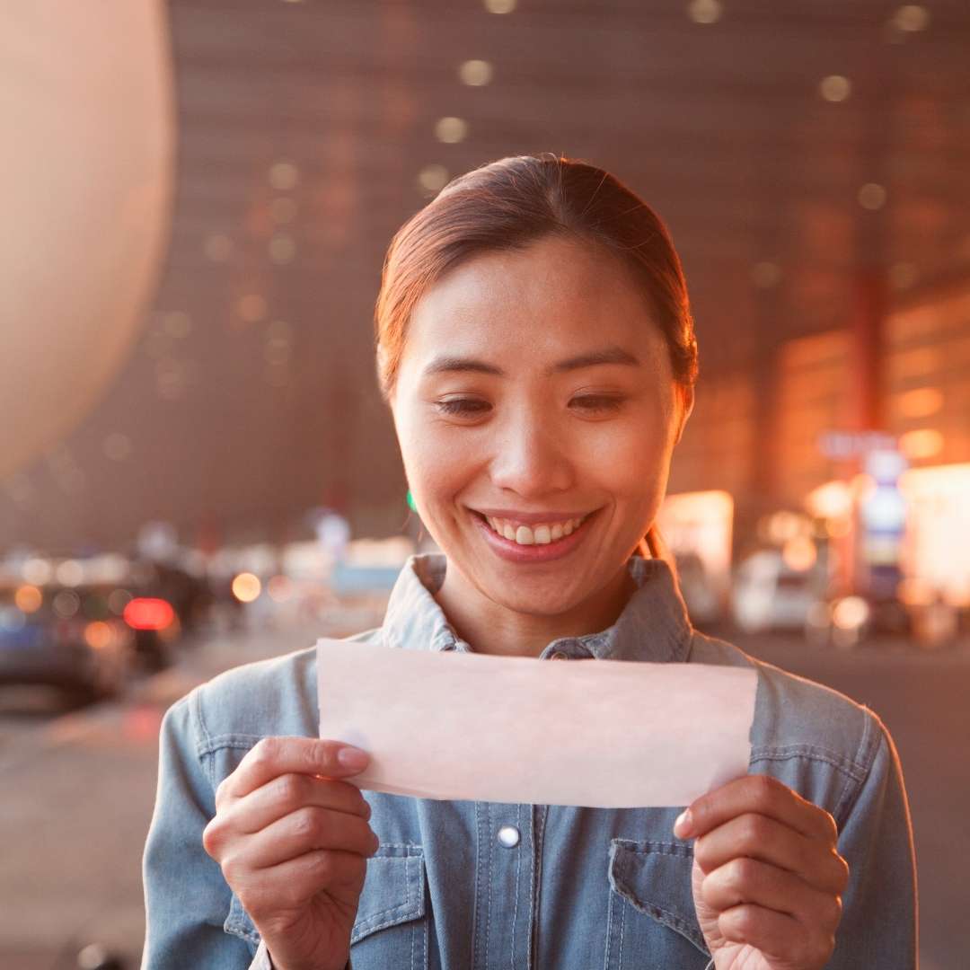 Happy woman looking at a plane ticket