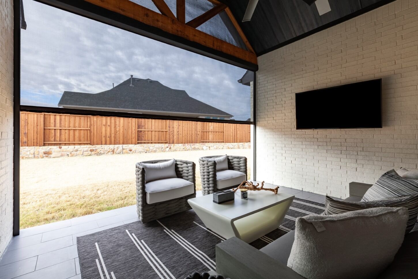 Outdoor patio with retractable shade, modern seating, and TV.