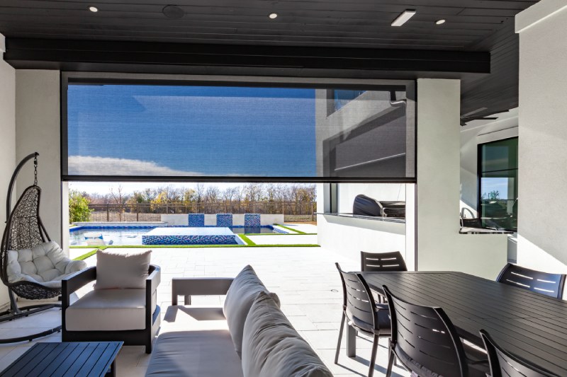 Outdoor patio with motorized shade, overlooking pool.