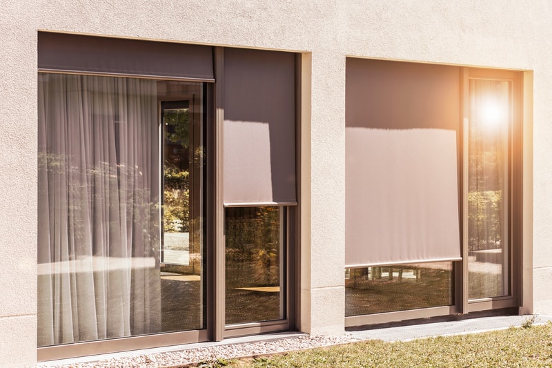 Modern home exterior with roller shades and sheer curtains.