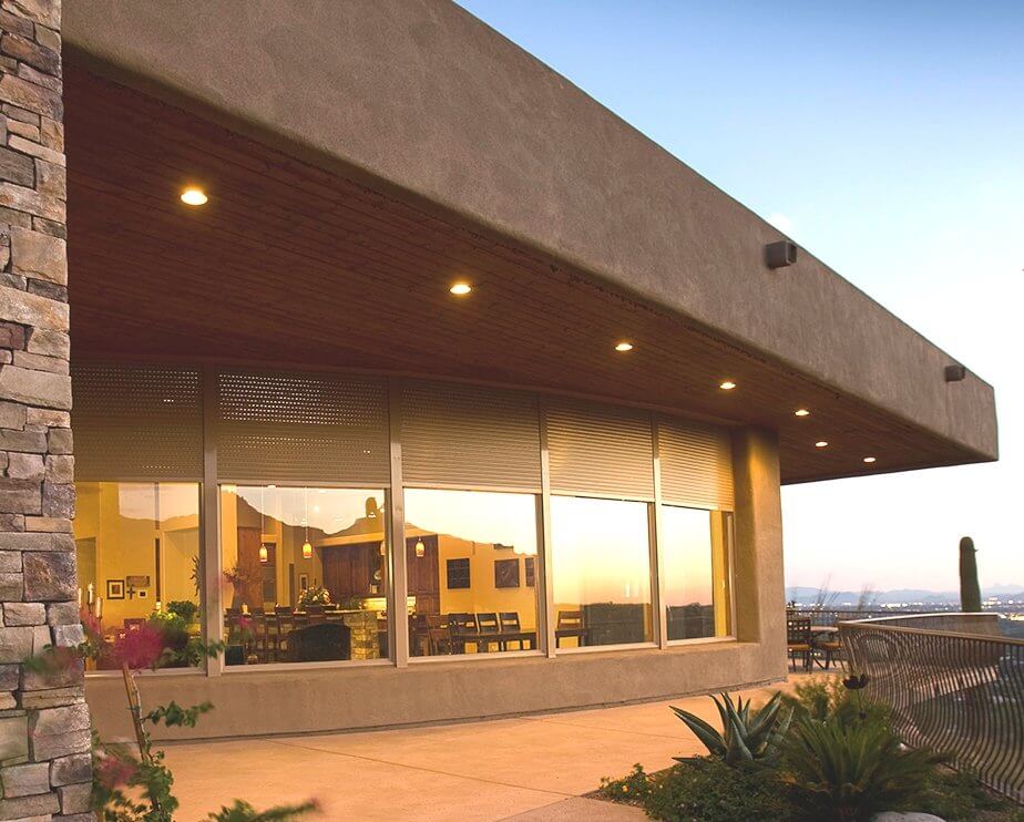 Exterior view of modern house with large windows and outdoor blinds.
