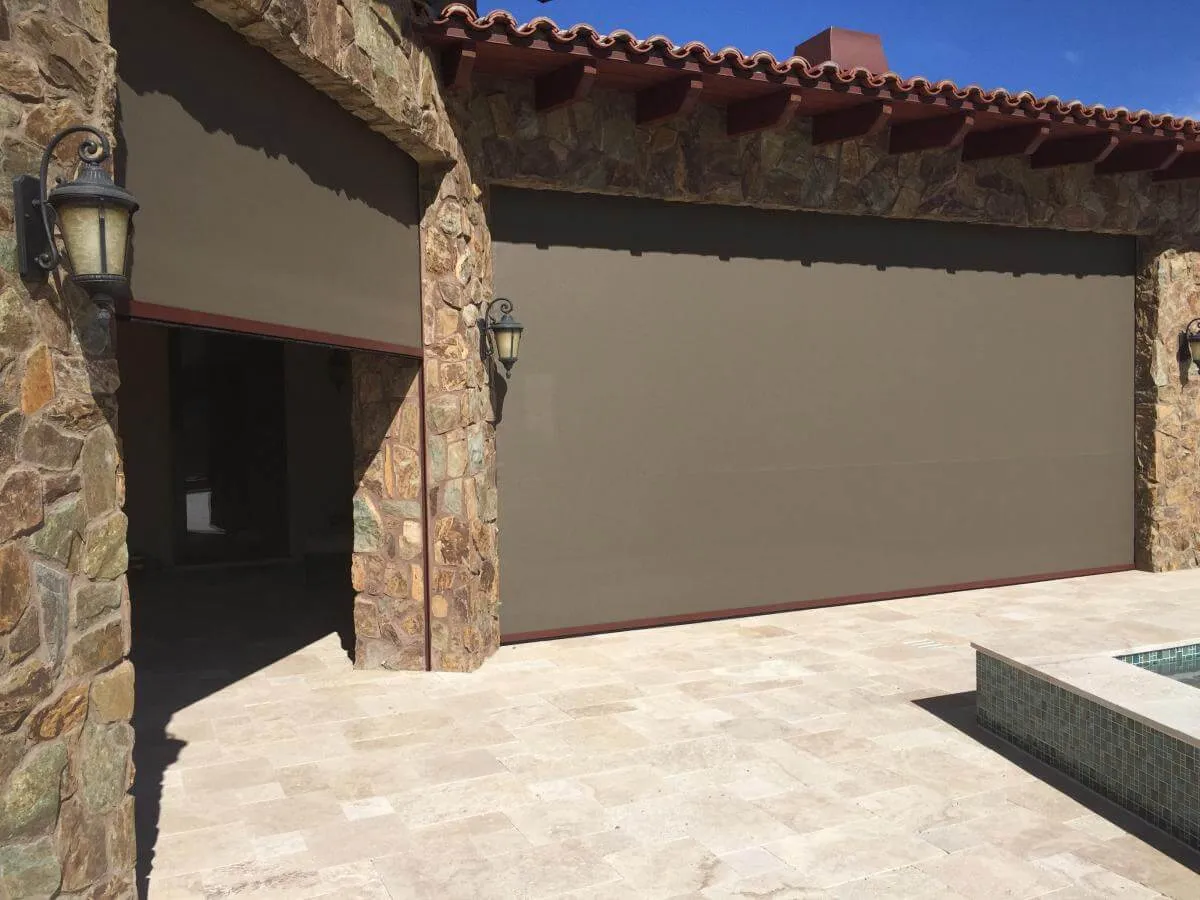 Large outdoor patio roller shade on stone building.