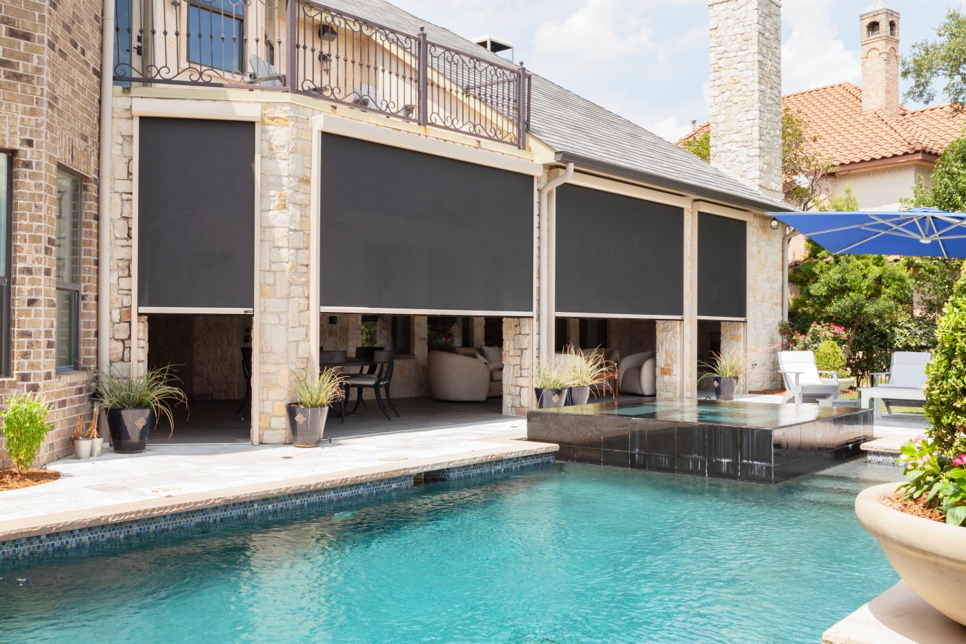 Outdoor patio with roll-down screens by a pool