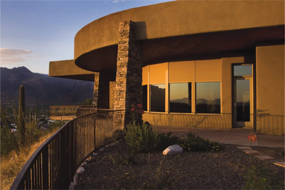 Rounded building with closed rolling shutters at sunset.