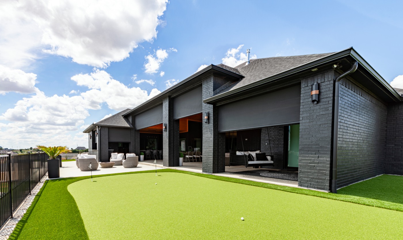 Backyard with patio, golf green, and window shades.