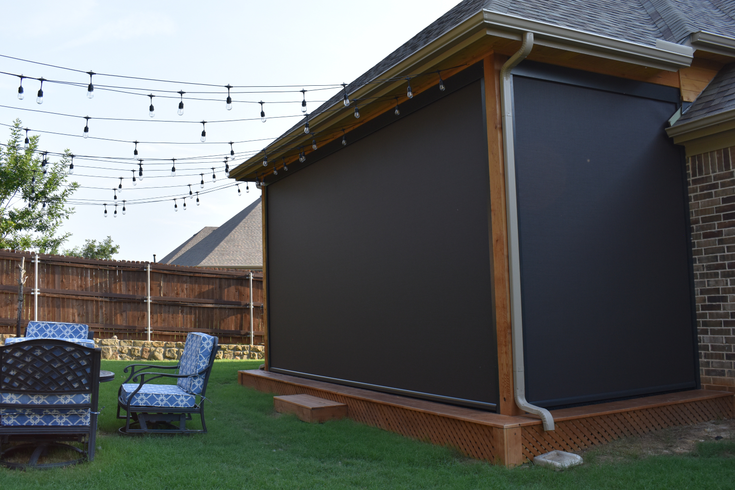 Motorized exterior screens enclosing a backyard patio for pet safety.