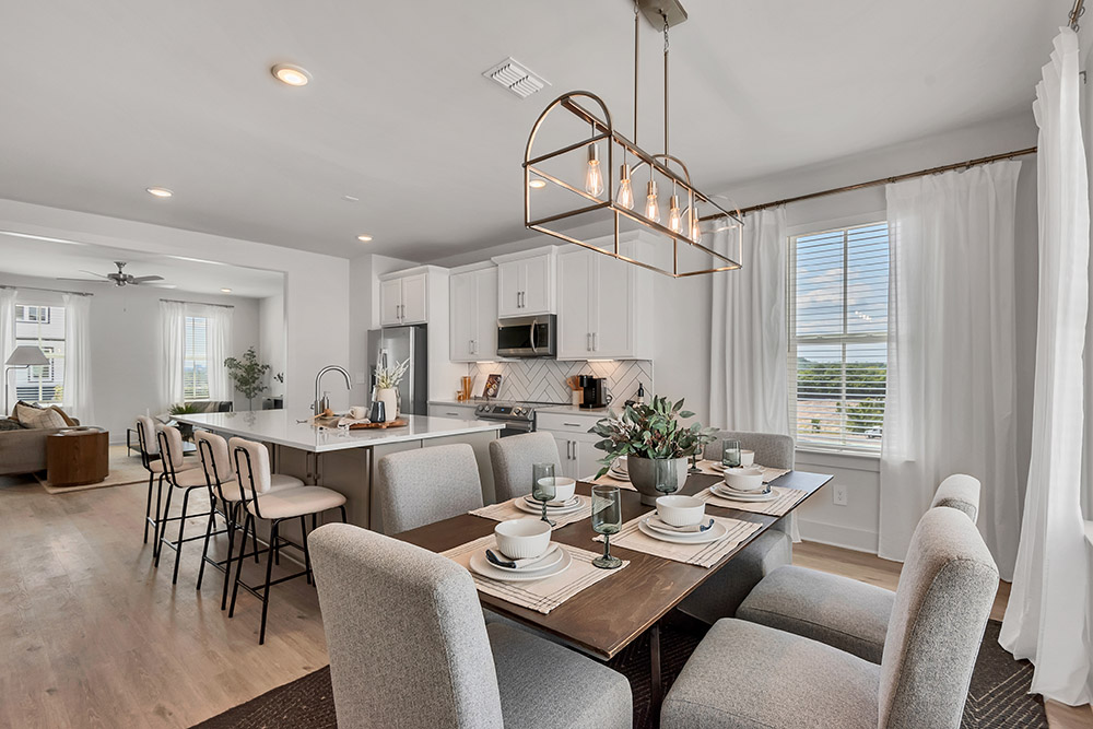 Breakfast table with a kitchen and island behind it.