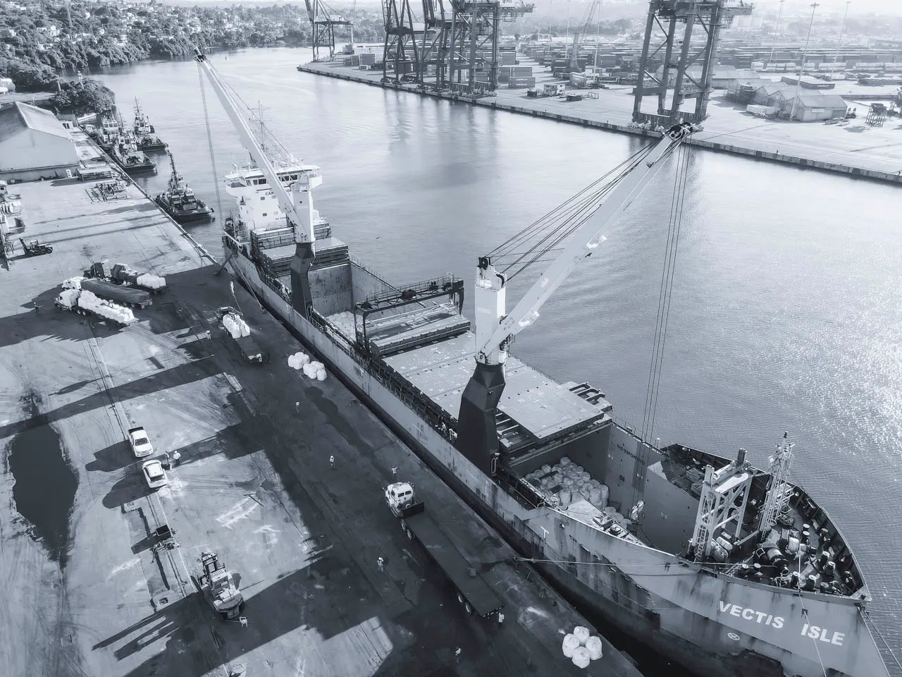 Wide aerial view of Vectis Isle cargo ship docked at an international port: Showcasing breakbulk supply chain and global maritime logistics infrastructure.