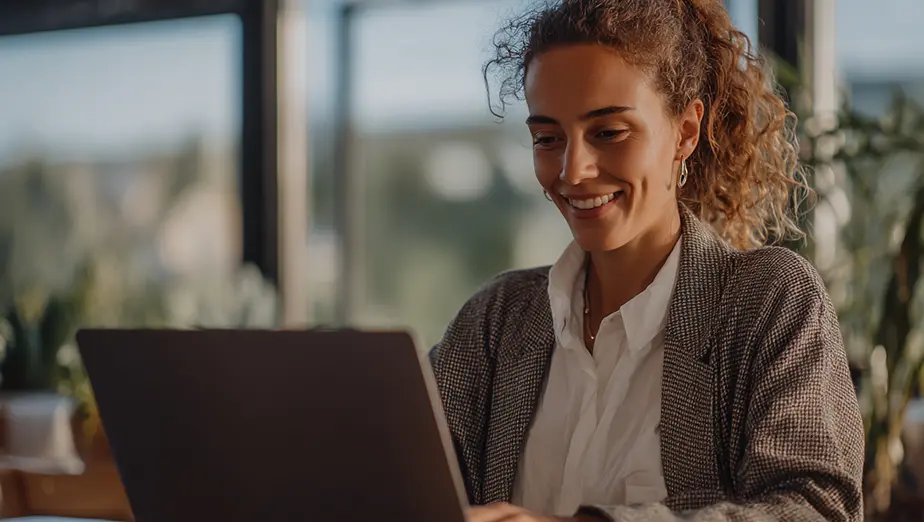 Mujer sonriente realizando ejercicios guiados por la plataforma Fisify desde su ordenador, representando la fisioterapia digital personalizada y el entrenamiento en casa con seguimiento inteligente.