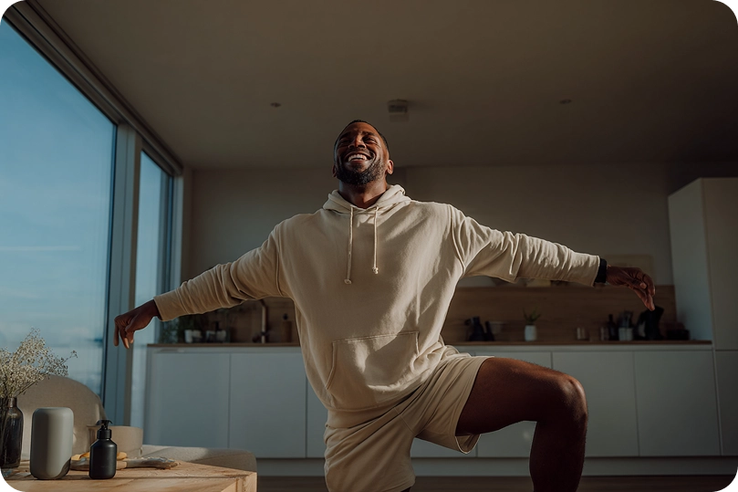 Hombre realizando ejercicio en casa con una sonrisa, símbolo del bienestar y la salud física que ofrece la fisioterapia digital personalizada de Fisify.