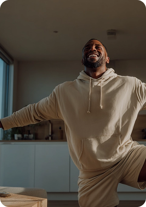 Hombre realizando ejercicio en casa con una sonrisa, símbolo del bienestar y la salud física que ofrece la fisioterapia digital personalizada de Fisify.