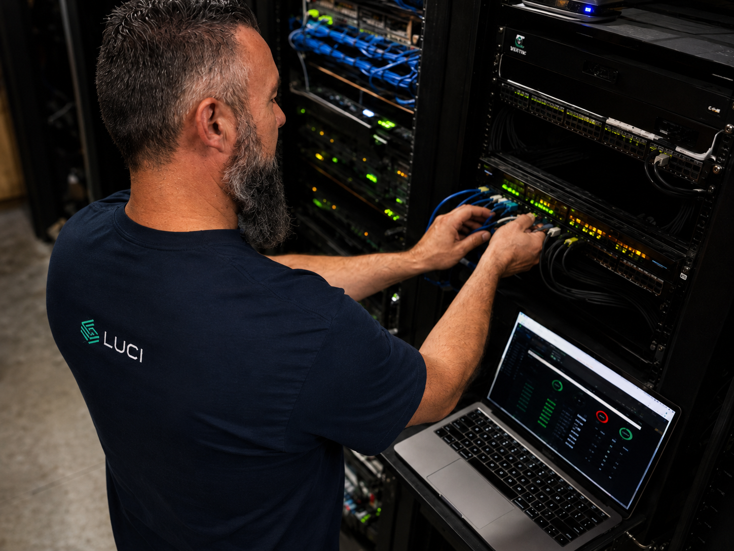 LUCI technician routing blue ethernet cables in a server rack during a casino AV installation