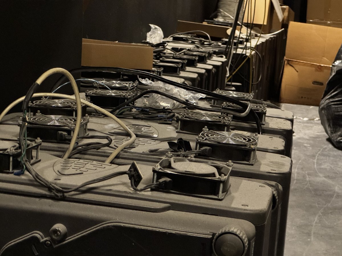 Row of dusty legacy projectors lined up on the floor before removal &mdash; the 20+ projectors replaced by the LED wall