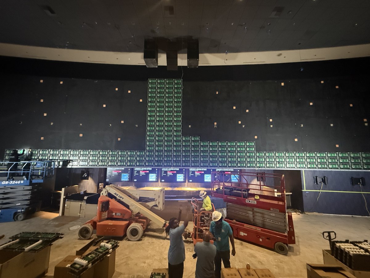 Construction of the 106-foot curved LED wall at Aliante &mdash; green LED tiles being installed on the curved mounting structure with scissor lifts and crew on the floor