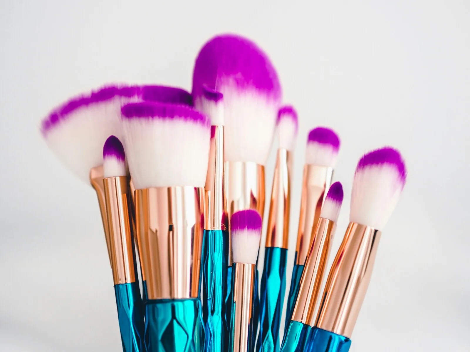 Makeup brushes against a white wall.