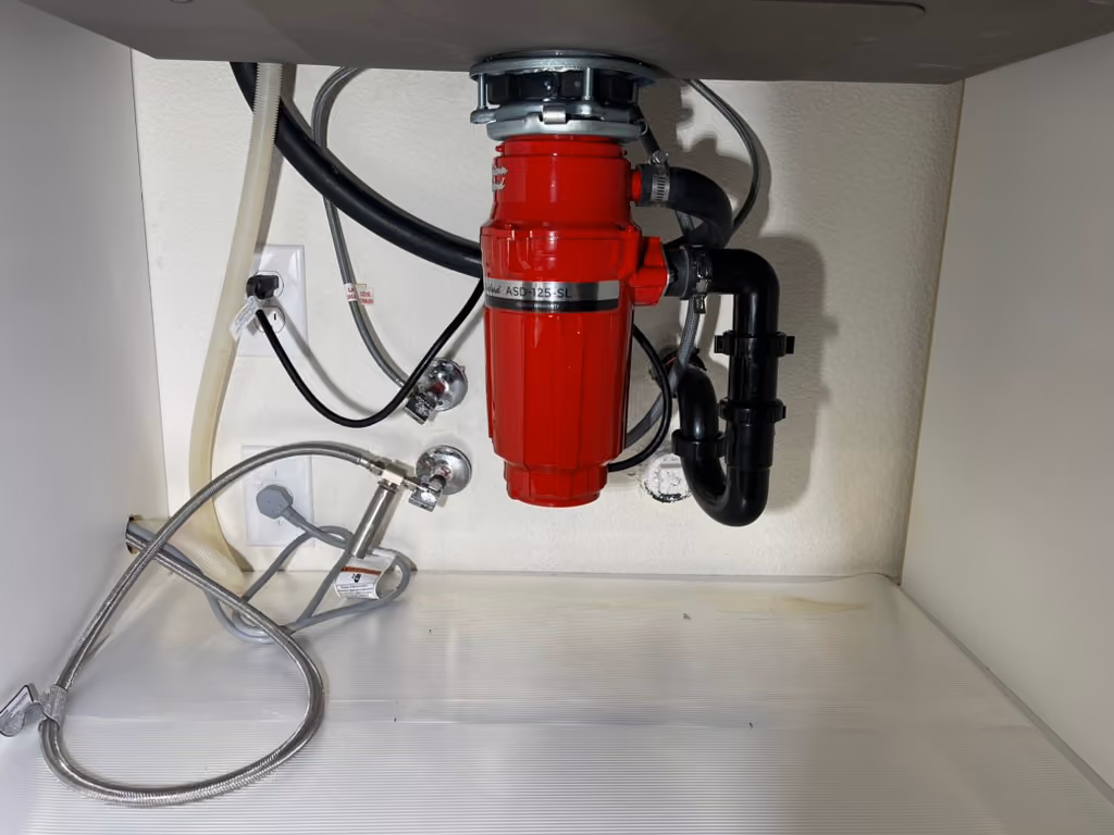 A garbage disposal installed under a kitchen sink.