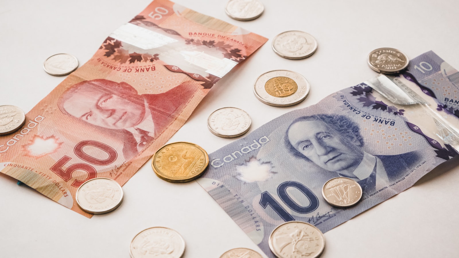 Canadian dollar bills and coins ($50, $10, dollar) on a white background