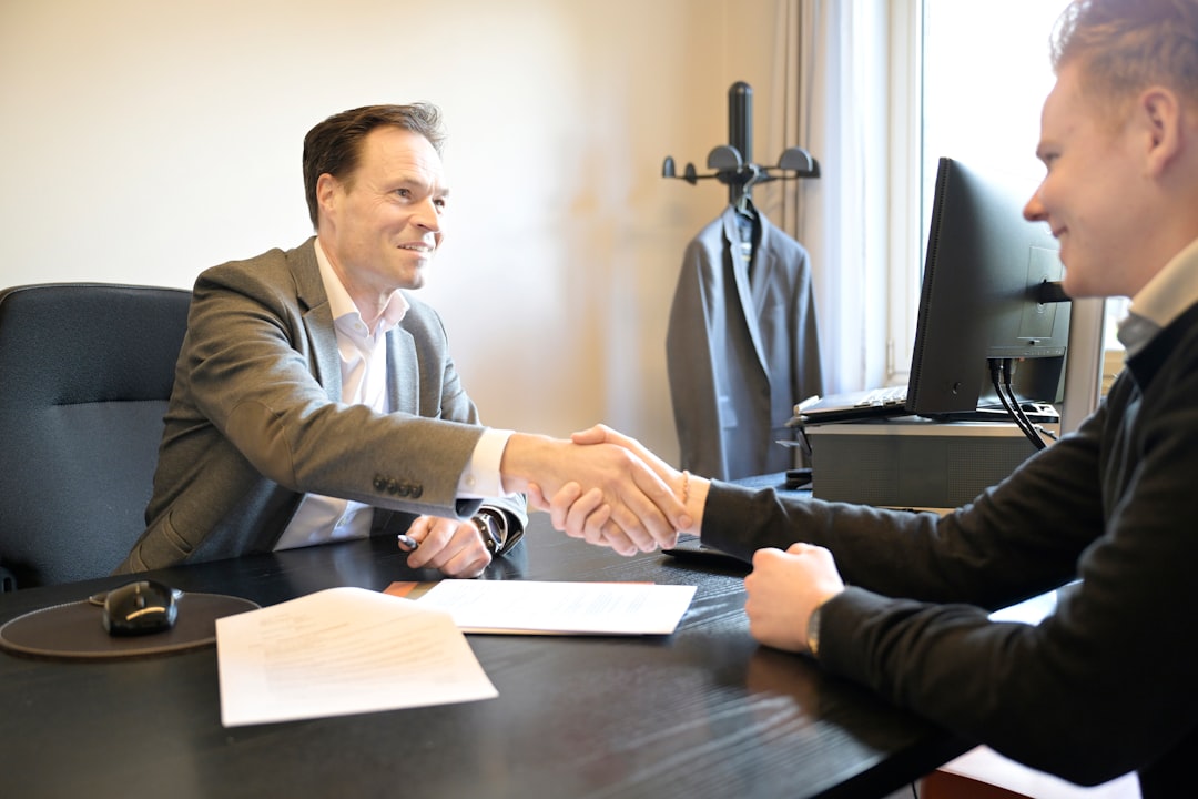 Two professionals shaking hands in an office, a symbol of human trust