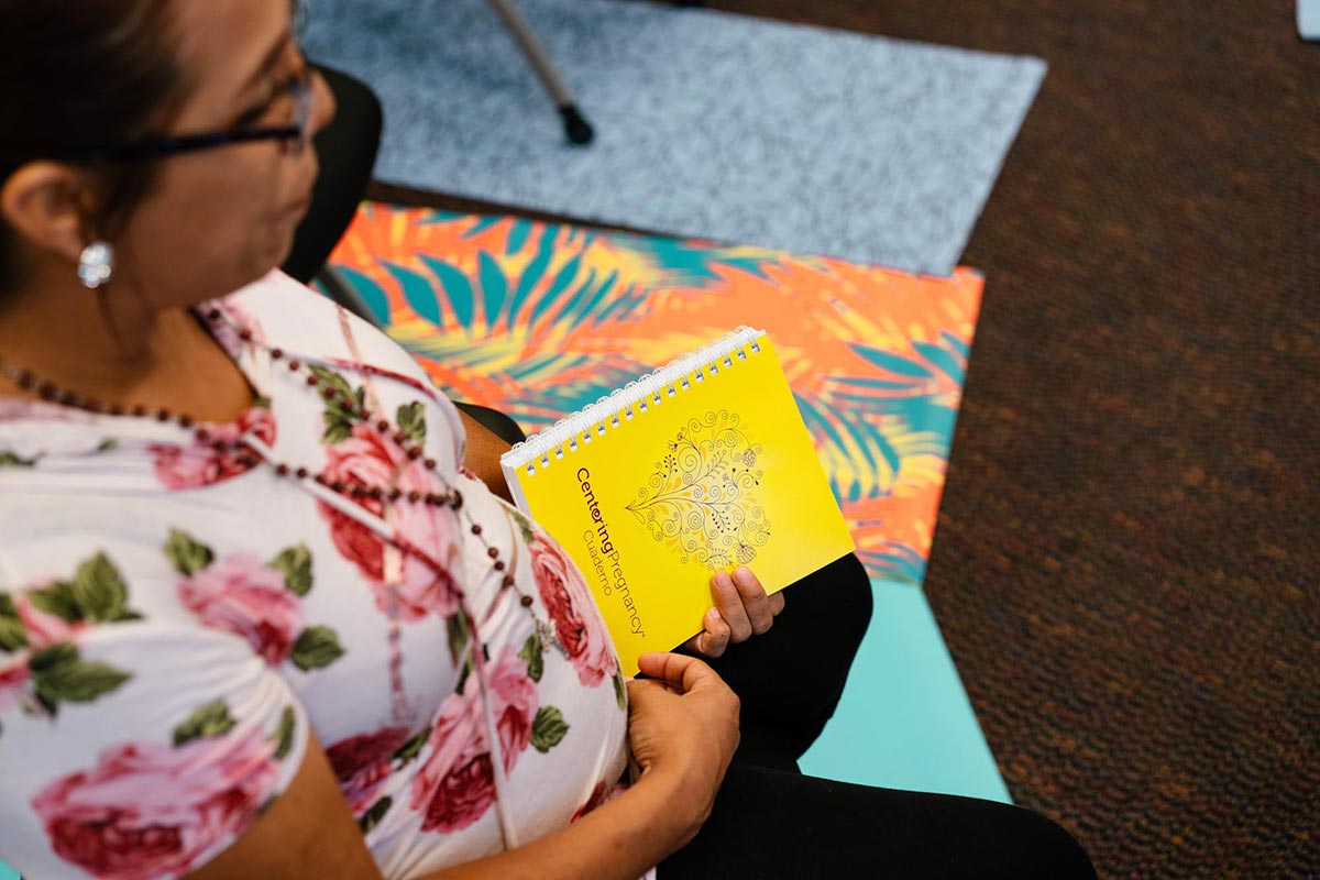 A pregnant woman holds a Centering Pregnancy brochure in hand during a group session