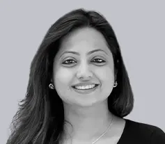 Portrait of a smiling woman with long hair against a plain background.