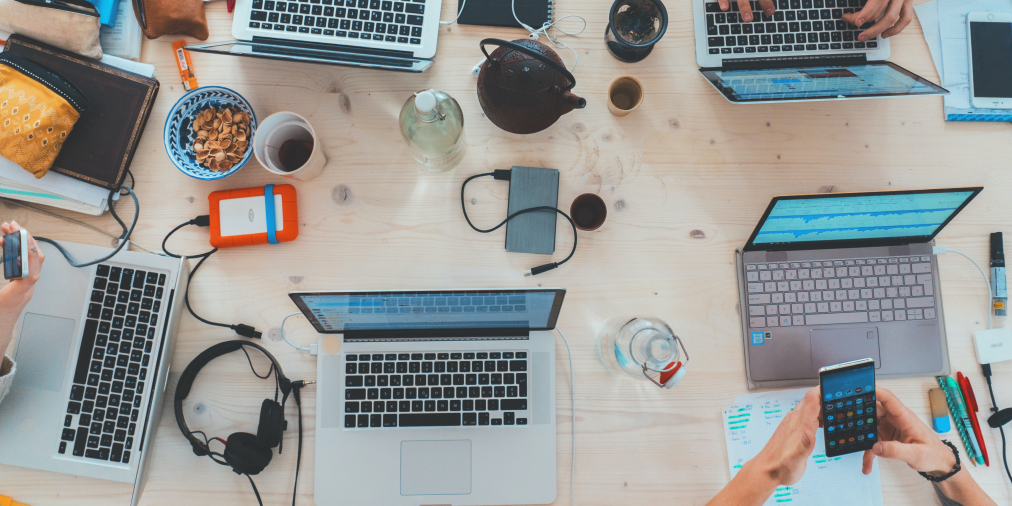Equipo de agencia de marketing trabajando entre laptops y dispositivos
