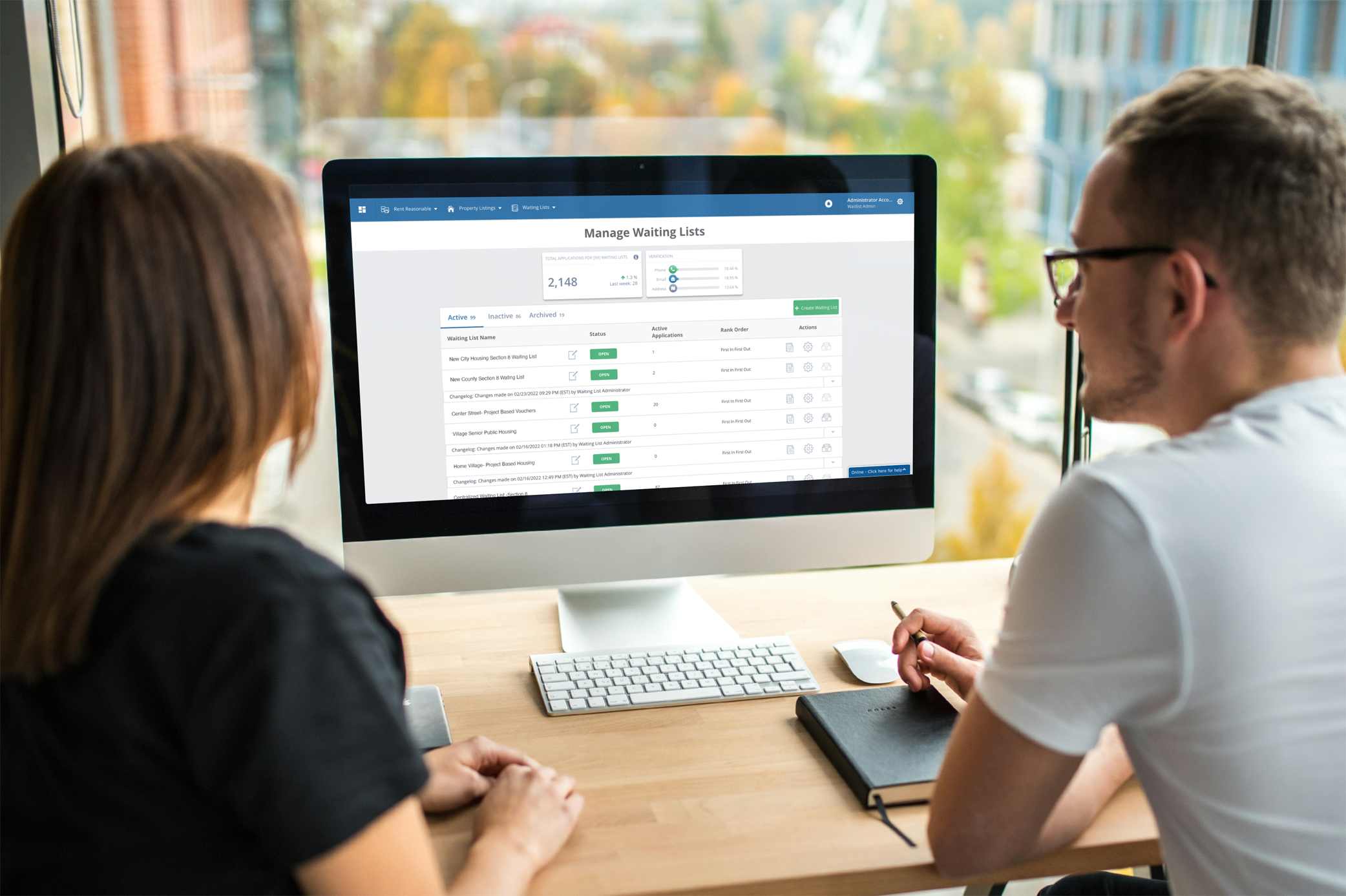Two people sitting at a desk looking at a computer with RevoList software on the screen.