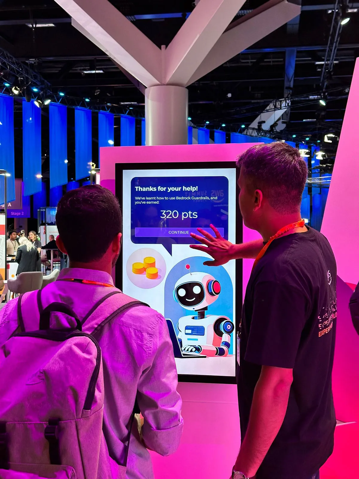 Two men interacting with a digital touchscreen display showing a robot and a message about earning 320 points.