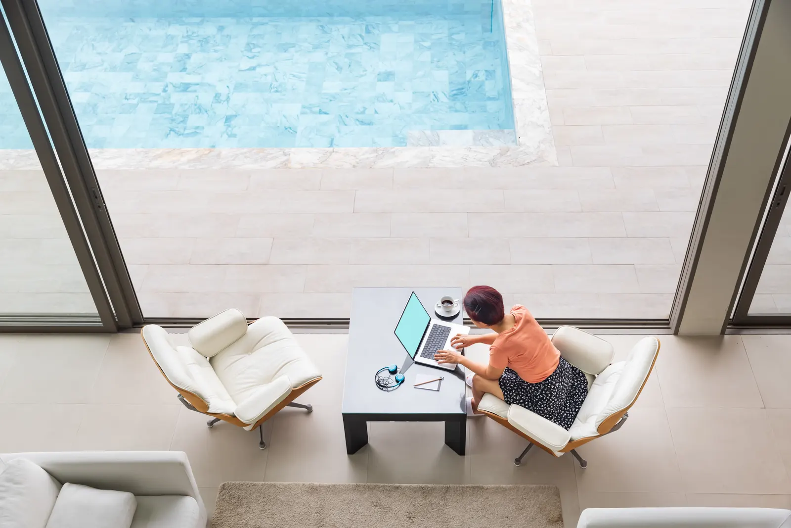 Picture of a busy businesswoman professional working at the laptiop at the swimming pool while she is on holiday.