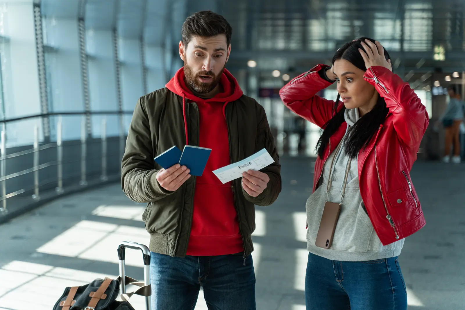 Young couple in the airport having stress in their relationship. One takes responsability on all the admin work, travel documents while the other one forgot important items at home and getting in panic mode.