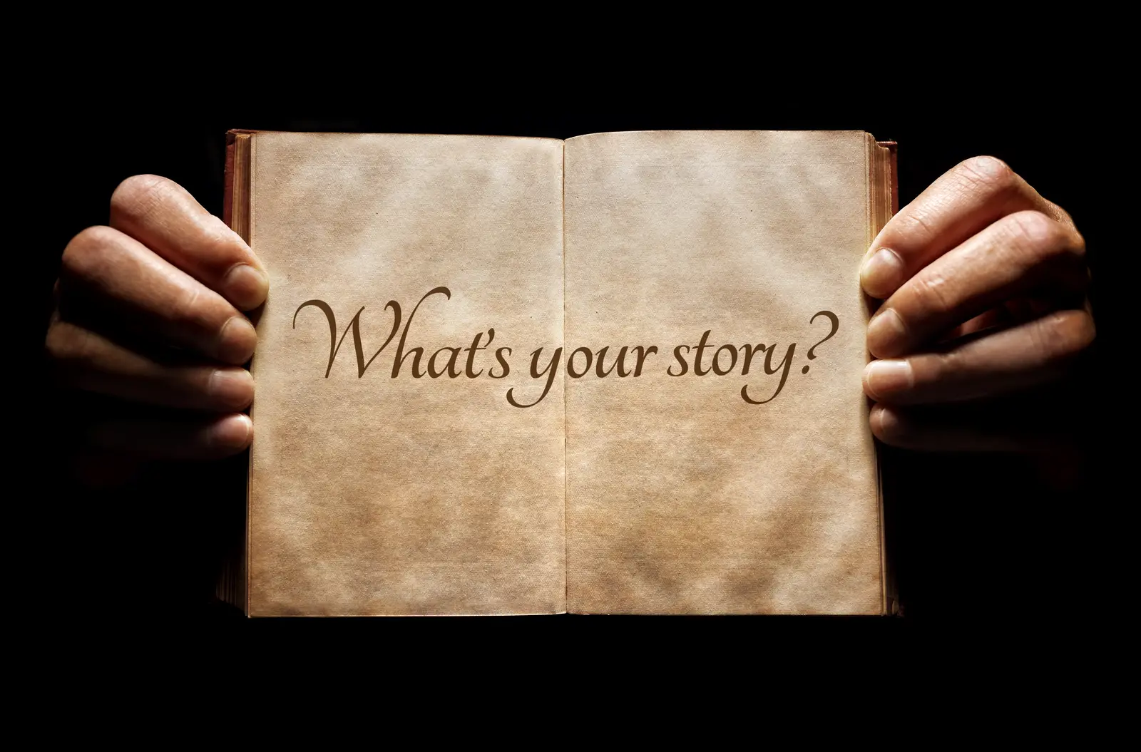 picture of two hands holding an open notebook saying "What's your story?"