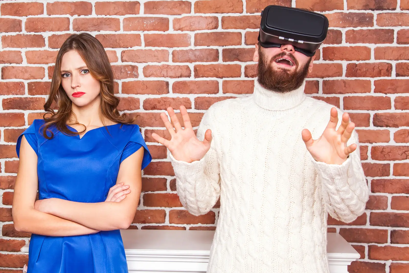 Picture of a man immersed in VR gaming while his wife is upset on his behaviour.