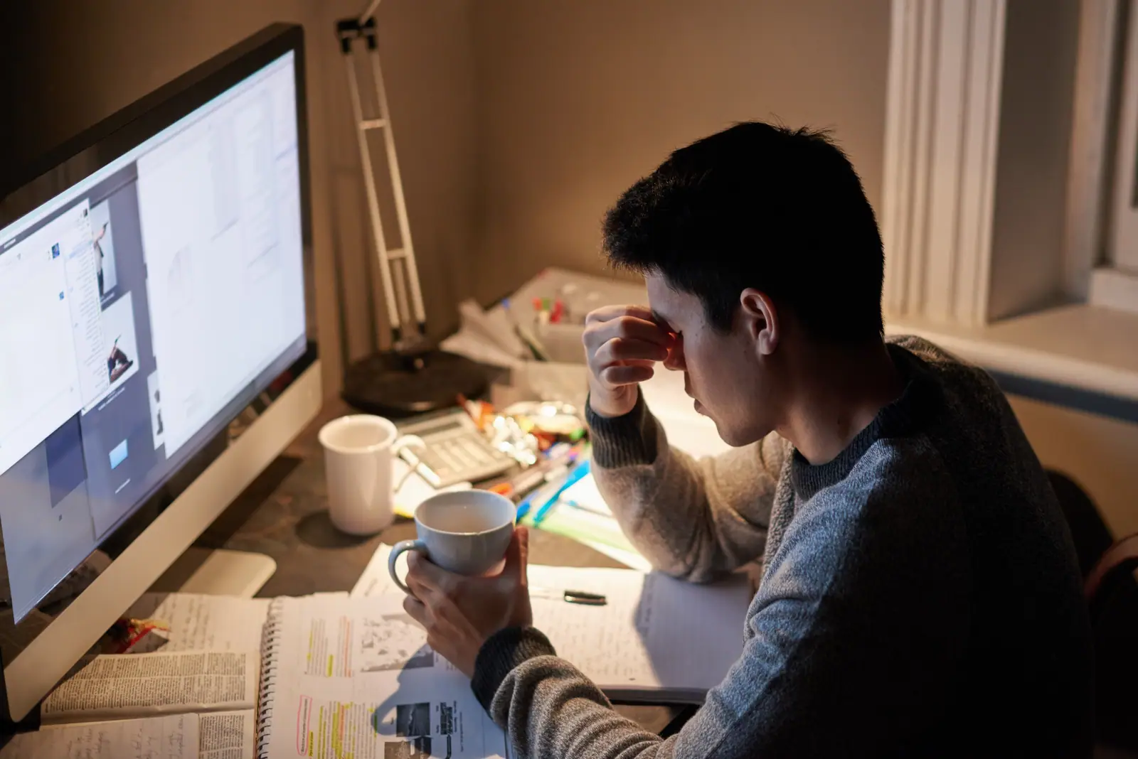 Picture of a student late at night, studying at the table compensating by staying late to study for A levels.