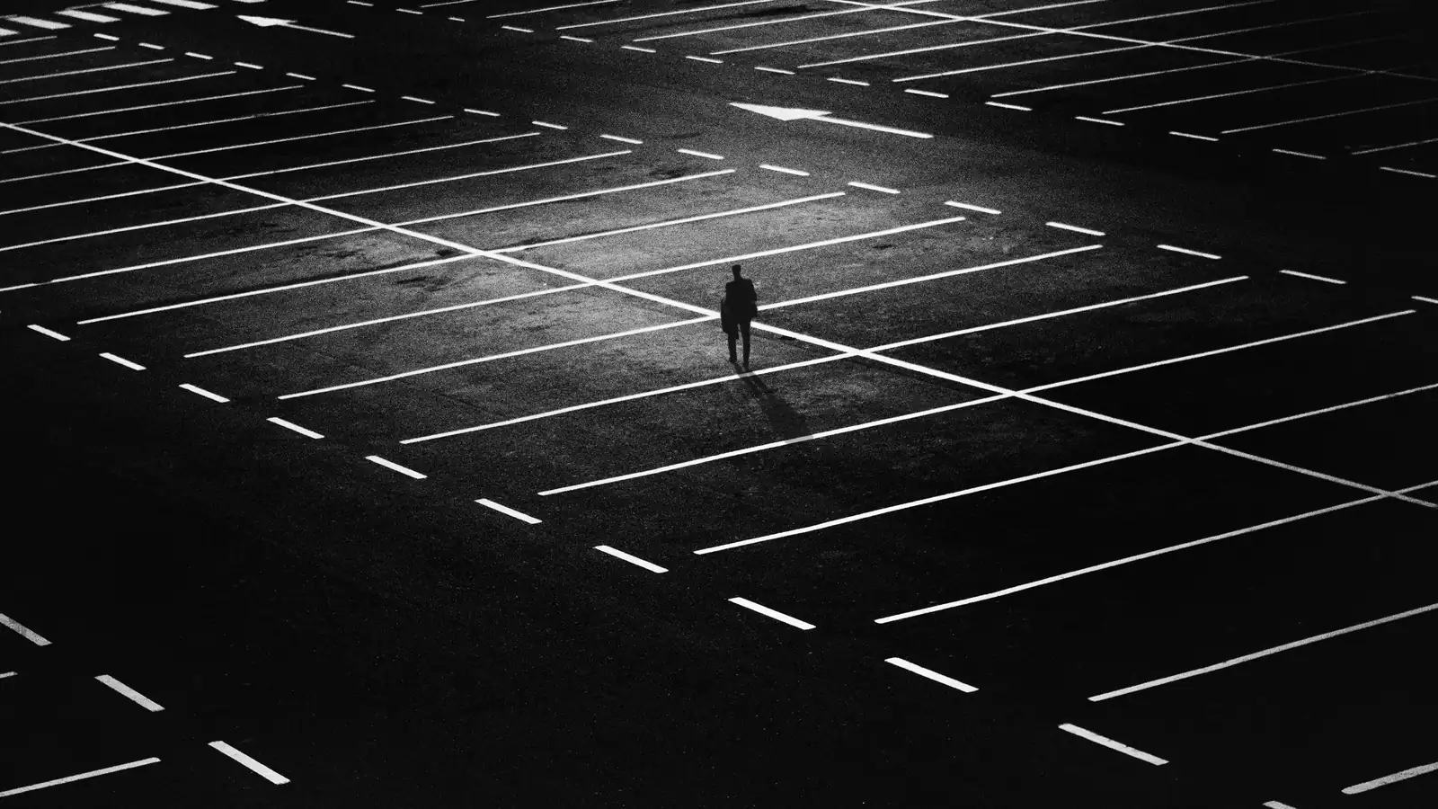 Picture of a man in a dark parking lot, now left alone after the unseen partner scaffolding disappearead.