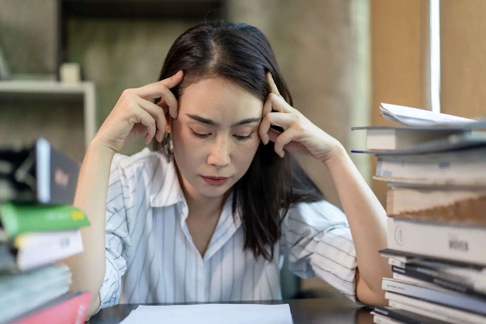 An adult professional woman being stressed in the office due to admin work.